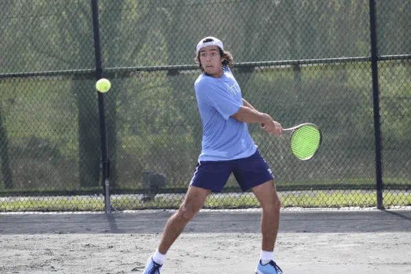 Male student playing tennis