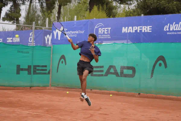 Male student mid-swing playing tennis