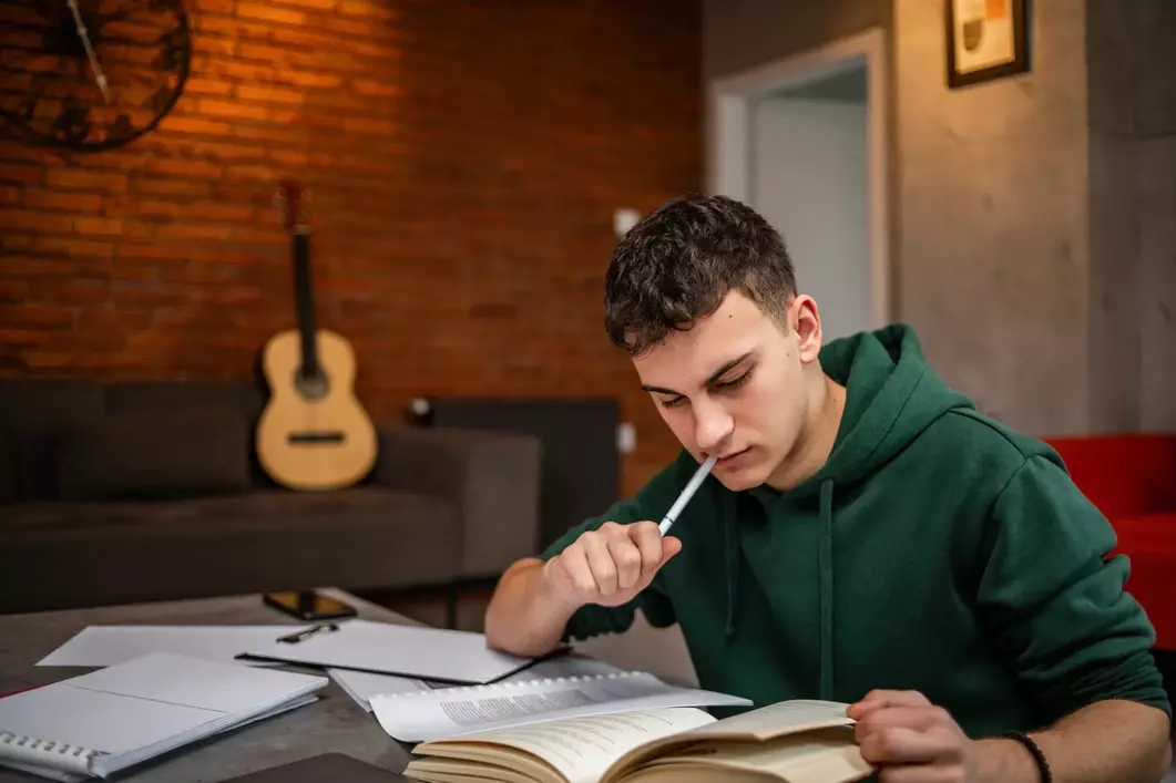 male student studying, guitar in the background