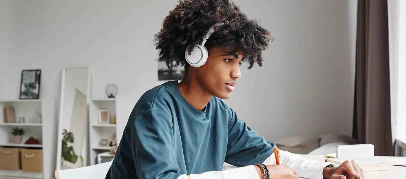 Male student writing with headphones