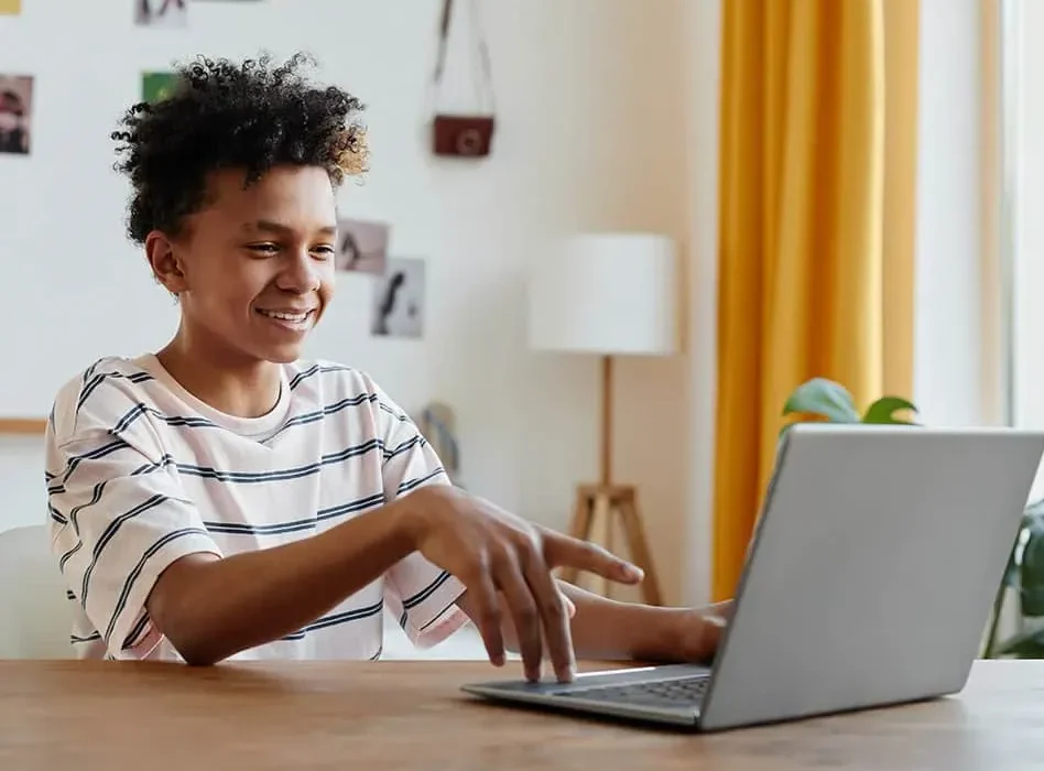 Student smiling while pointing at laptop