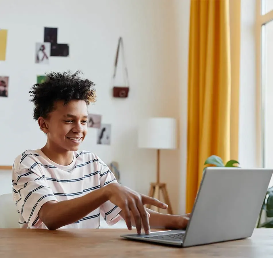 Student smiling while pointing at laptop