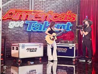 Camille singing at Americas got talent on stage with a guitar 