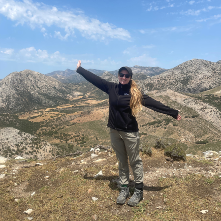 Angelina Kossoff at the top of a mountain smiling in her Laurel Springs jacket.