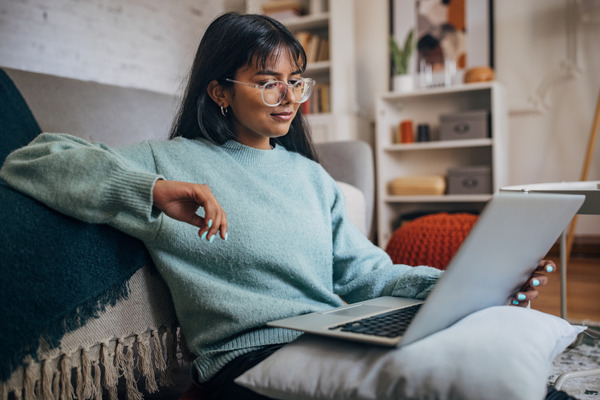 Girl in blue shirt and glasses working on a laptop