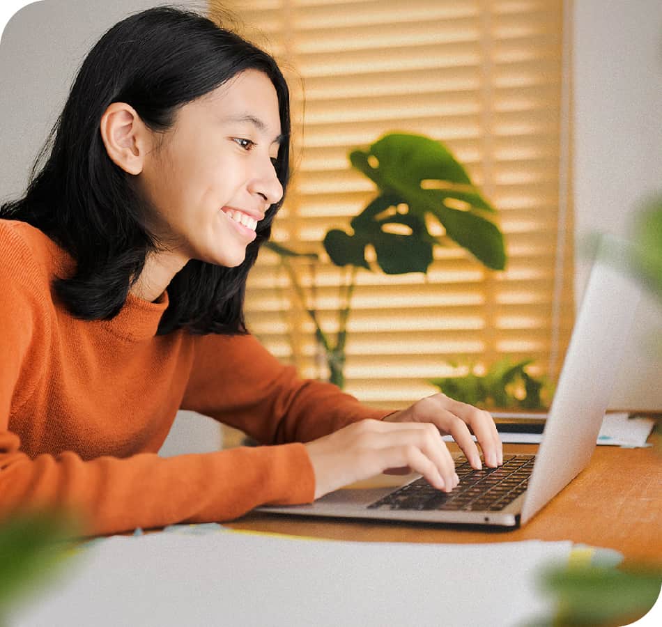 grinning student typing on his laptop