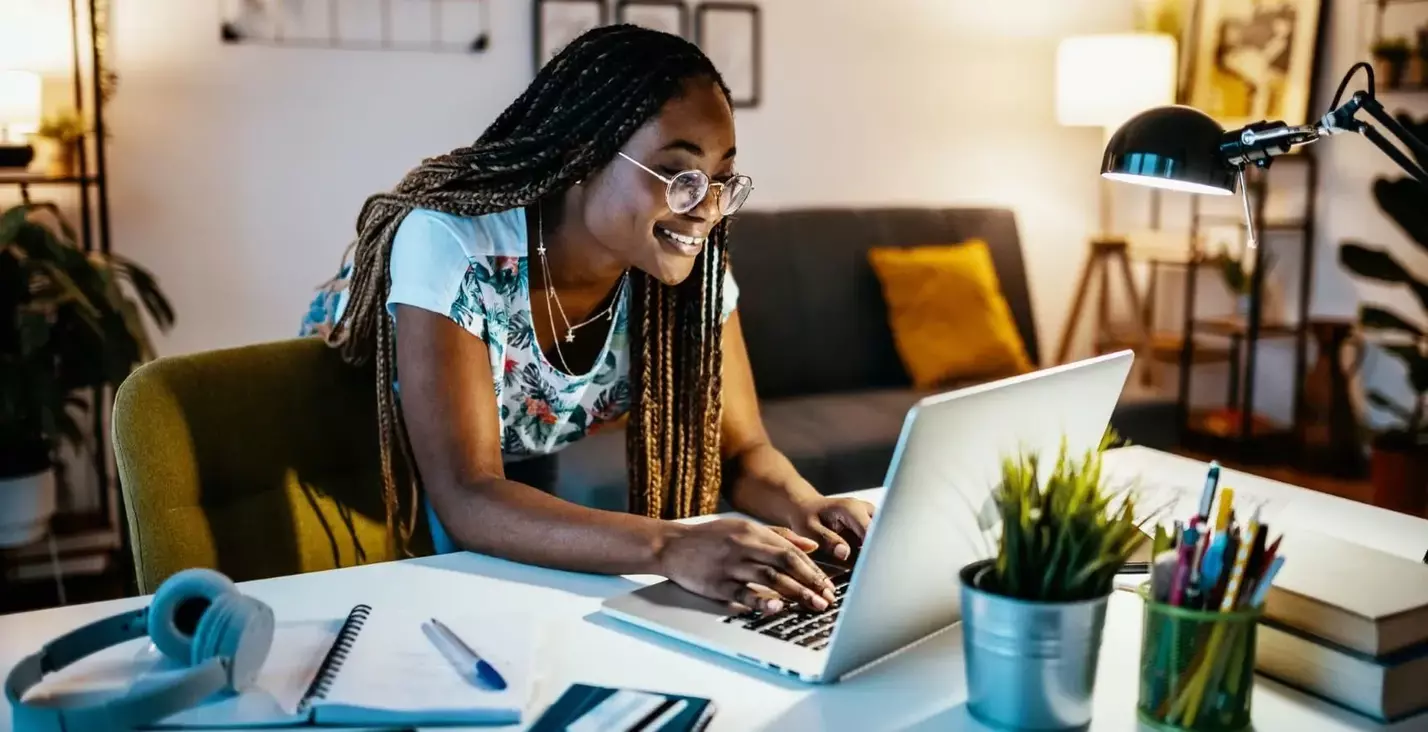 Female student smiling and typing on a laptop